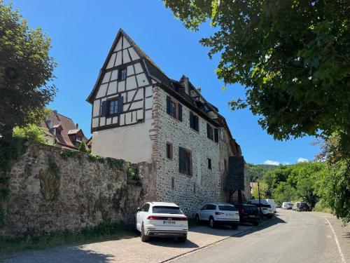 Domaine La Cour Des Nobles - Demeure, Maison et Appartements au coeur de Riquewihr في ريكيوير: مبنى قديم مع سيارات تقف على جانب شارع