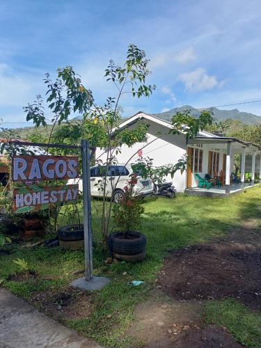 a house with a sign in front of it at Rago's Homestay in Kelimutu