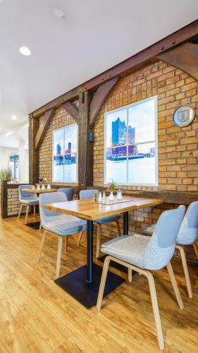 a dining room with tables and chairs and a brick wall at Hotel Kreuzer in Wedel