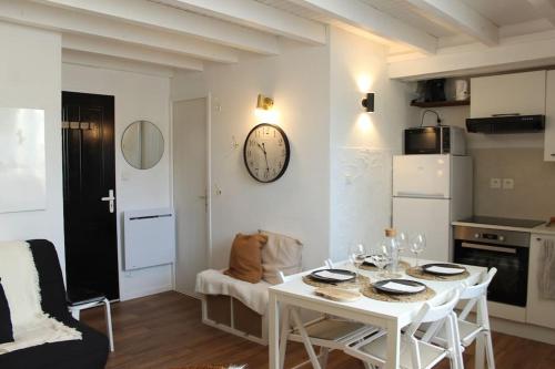 a kitchen with a white table and a clock on the wall at Le P'tit Hélios 4-6 personnes - Centre ville de Barèges in Barèges