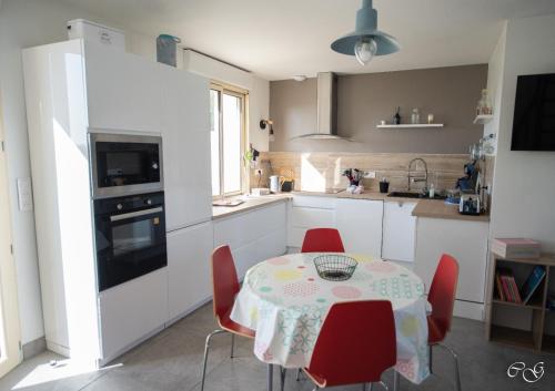 a kitchen with a table and red chairs in a kitchen at GITE ARC EN CIEL BLEU in Férel