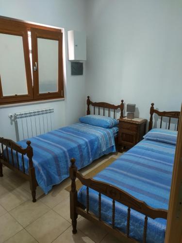 a bedroom with two beds and a table and windows at La Casa al Centro in Rionero in Vulture