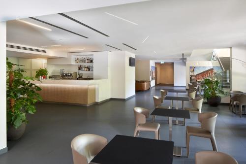 a hotel lobby with tables and chairs and a bed at UNAHOTELS Bologna Fiera in Bologna