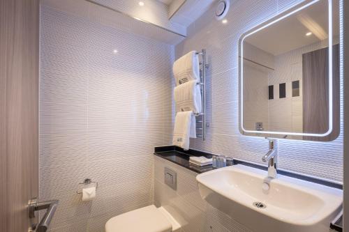 a bathroom with a sink and a mirror and a toilet at City Sleeper at Royal National Hotel in London