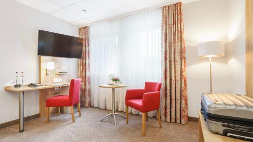 a hotel room with a desk and red chairs at Hotel Kreuzer in Wedel