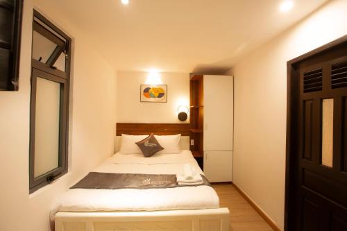 a small bedroom with a bed and a window at Carnival Hotel - Đà Lạt in Da Lat