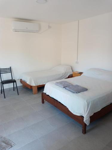 a room with two beds and a chair in it at Departamento Chacabuco in San Fernando del Valle de Catamarca