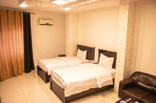 a hotel room with two beds and a chair at Sara Crown Hotel in Irbid