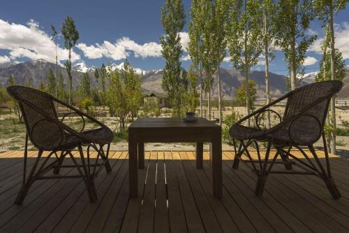 two chairs and a table on a deck at Nubra Ecolodge in Liekzan