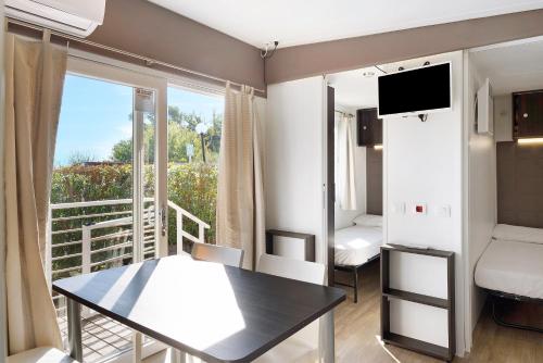 um pequeno quarto com uma mesa e uma varanda em Mobile Home Next 232 em Pietra Ligure