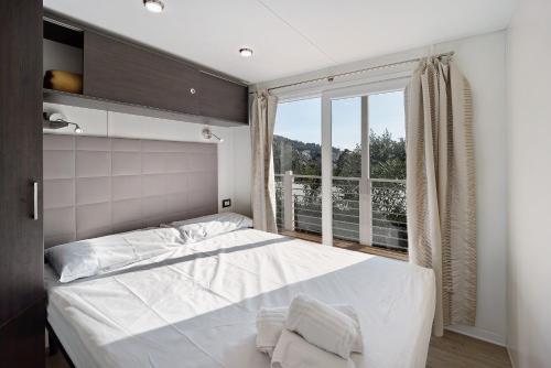 um quarto com uma cama e uma grande janela em Mobile Home Next 229 em Pietra Ligure