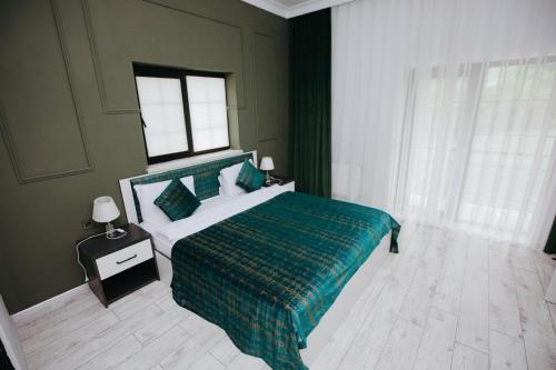 a bedroom with a bed with a green bedspread and a window at Castle Resort Spa Hotel in İsmayıllı