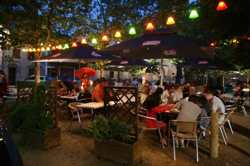 a group of people sitting at a restaurant under umbrellas at Hôtel Restaurant du Pêcheur in Lavoûte-Chilhac