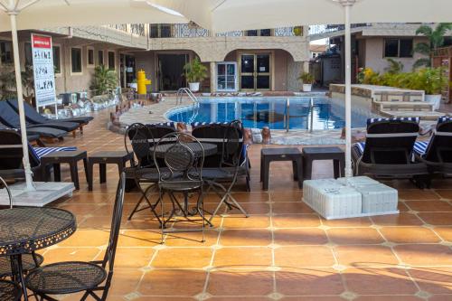 a patio with tables and chairs and a swimming pool at Lou Ralph Hotel in Accra