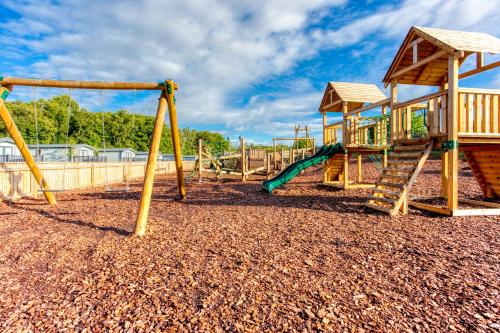 a playground with two swings and a slide at Lakeside Lodge, Green Hill Farm Holiday Village in Salisbury