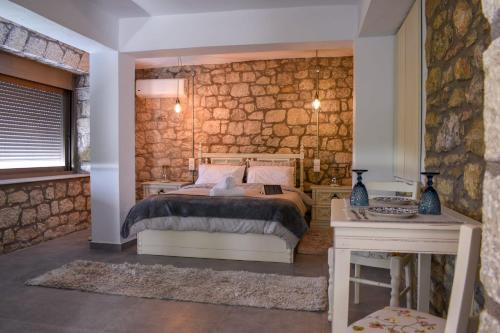 una camera con letto e parete in pietra di Coastal Stone Hideaway with Stunning Scenery a Kitriaí