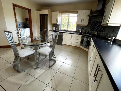 a kitchen with a glass table and chairs in it at Drumbar Lodge in Carterʼs Bridge