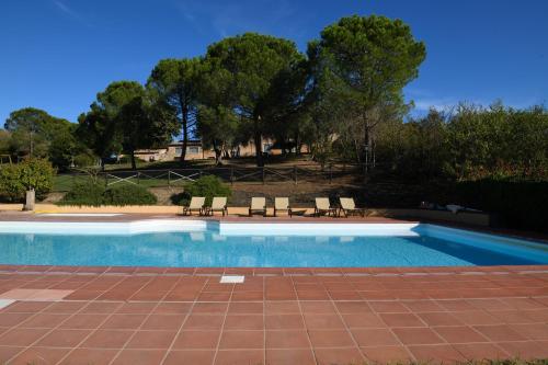 una piscina con sillas y árboles en el fondo en Podere San Giuseppe Montalcino, en Montalcino