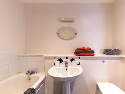 a white bathroom with a sink and a bath tub at Belfast Apartment in Belfast