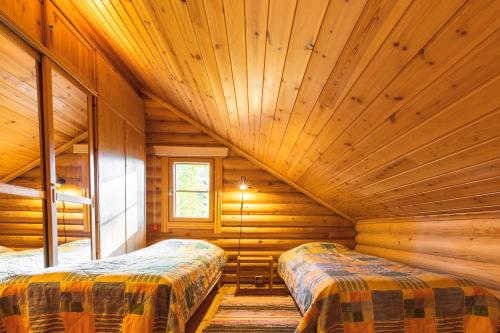 a room with two beds in a log cabin at Taikalevi Apartment in Levi