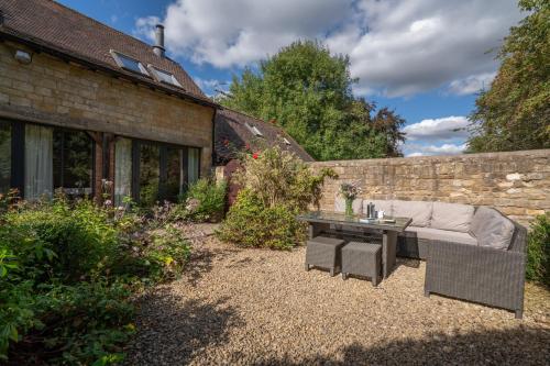 a patio with a couch and a table in a yard at Barn End in Chipping Campden