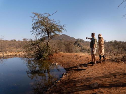 two people standing next to a body of water at Phomola Manor Holiday Home in Phalaborwa