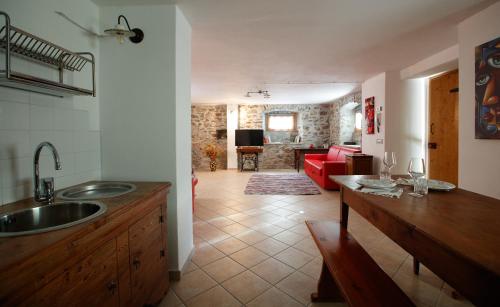 eine Küche mit einem Waschbecken und ein Wohnzimmer in der Unterkunft IL COMO' DELLA CIVETTA - Taverna “La Fenice” in Stazzona