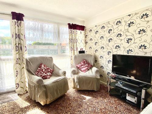 a living room with two chairs and a flat screen tv at Quiet and Comfy 2- bedroom Holiday Chalet, walk to the beach, Norfolk in Great Yarmouth