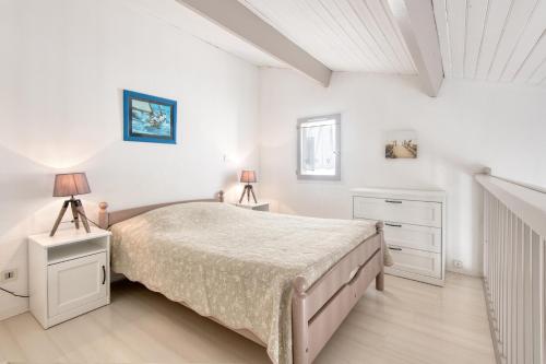 1 dormitorio blanco con 1 cama y 2 lámparas en Appartement Océanis avec Piscine proche du port, en Saint-Martin-de-Ré