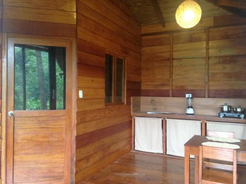 cocina con paredes de madera, puerta y mesa en La Musa Verde, en Tarapoto