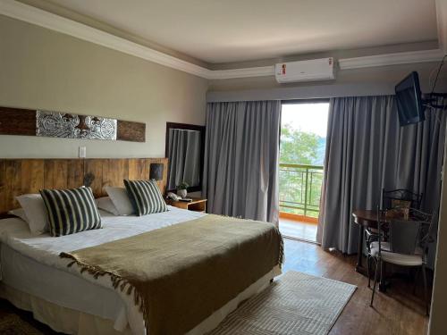 a bedroom with a large bed and a large window at Hotel Pousada Shangri-la in Serra Negra