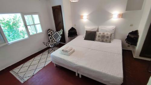 a small bedroom with a white bed and a chair at Logis Hôtel & Restaurant du Parc in Gémenos