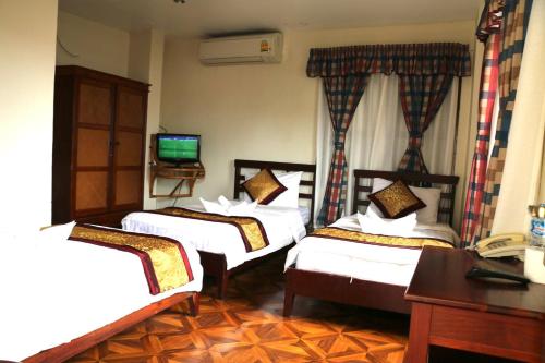 a hotel room with three beds and a television at Mali Namphu Hotel in Vientiane