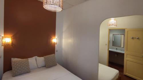 a room with a bed and a mirror and lights at Logis Hôtel & Restaurant du Parc in Gémenos