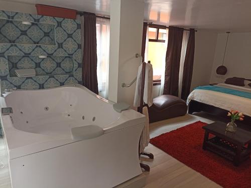 a bathroom with a tub and a bedroom with a bed at Posada J in Baños