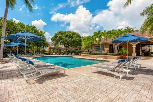 a swimming pool with lounge chairs and umbrellas at Luxurious Apartments with Pool and Gym at Boynton Beach in Boynton Beach