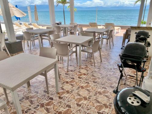 a restaurant with tables and chairs and the ocean at Suites Atlas - Ocean Front in Bucerías