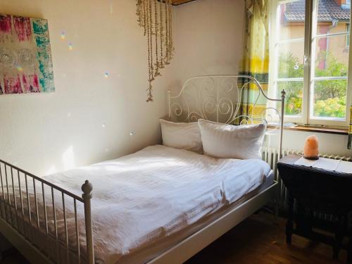 een slaapkamer met een bed met witte lakens en een raam bij Trad. Blackforest House in Ettenheim