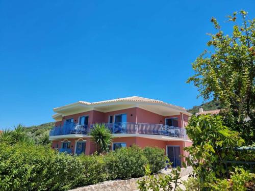 una casa rosa en la cima de una colina con árboles en Julietta Suites, en Argostoli