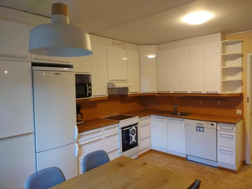 cocina con armarios blancos y mesa de madera en Asuntos-1 en Lahti