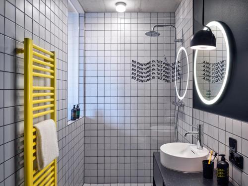 a white tiled bathroom with a sink and a mirror at STAYERY Köln Ehrenfeld in Cologne