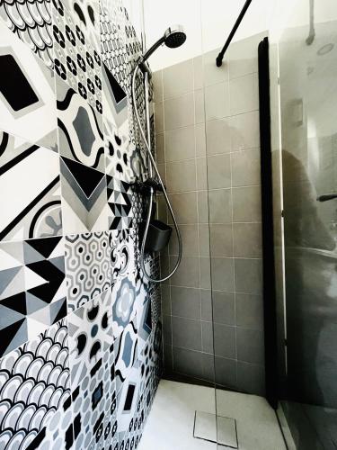 a shower in a bathroom with black and white tiles at A 2 passi dal mare Torre Faro LA PUNTA SeaHouse in Torre Faro