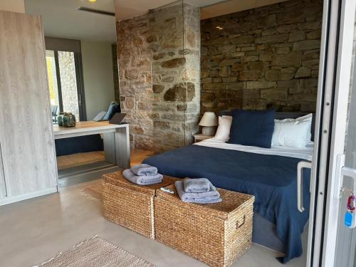 イオス島 チョーラにあるPrivate Five Br Luxury Peaceful Mylo Villa W Two Pools Close to Mylopotas Beachのベッドと石の壁のある寝室