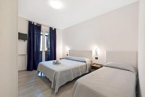 two beds in a room with blue curtains at Cà de Anto in Cisano sul Neva