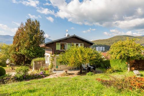 a small house in a field with mountains in the background at Chalet Les Tourelles in Aix-les-Bains