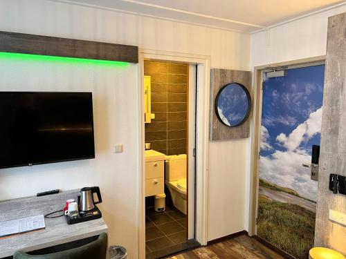 een badkamer met een toilet en een televisie aan de muur bij Hotel Nap in West-Terschelling