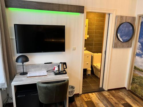 a room with a desk with a television on a wall at Hotel Nap in West-Terschelling