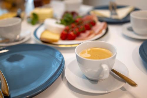 a cup of coffee on a table with plates of food at Pure Berlin Apartments - Luxury at Pure Living in City Center in Berlin