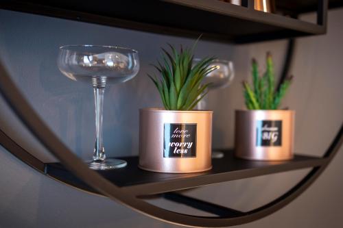 a shelf with a glass of wine and two potted plants at Pure Berlin Apartments - Luxury at Pure Living in City Center in Berlin