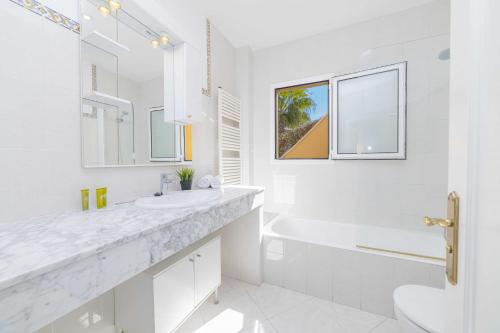 baño blanco con lavabo, bañera y aseo en Villa Arata, en Alcanada
